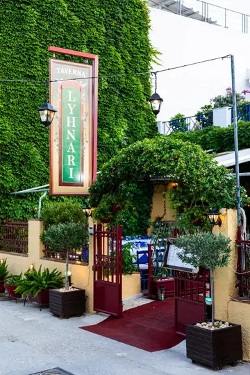 The entrance under a wall of ivy, with the taverna sign