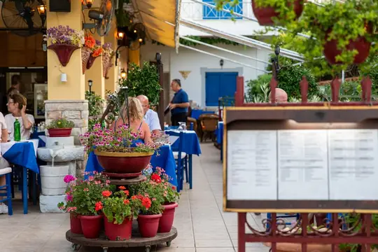 The courtyard with the menu board, flowering pots and guests at the tables