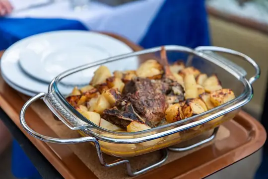 Roast lamb and potatoes brought to the table in its baking dish