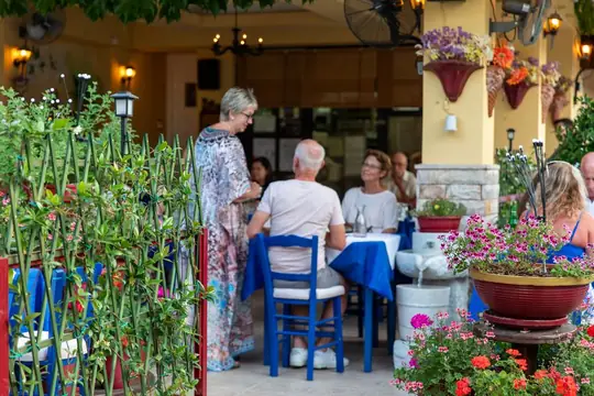 Guests, blue chairs and pots of geraniums in the courtyard